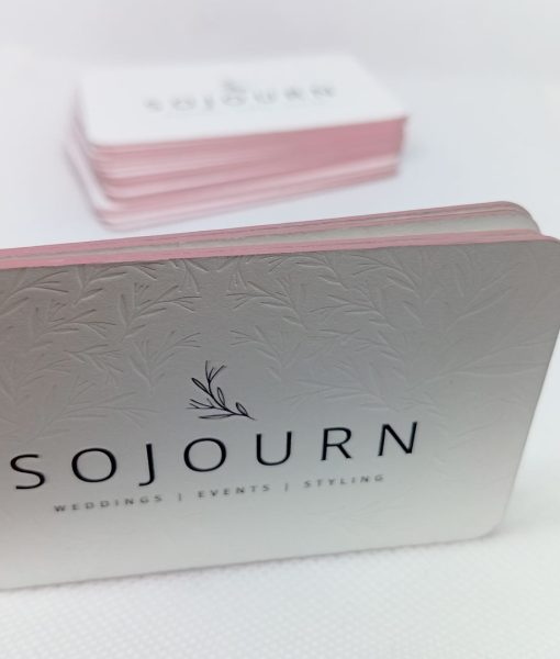 Stacked edge foiled business cards with front of card letterpress logo and in the out of focus business card stack in the background