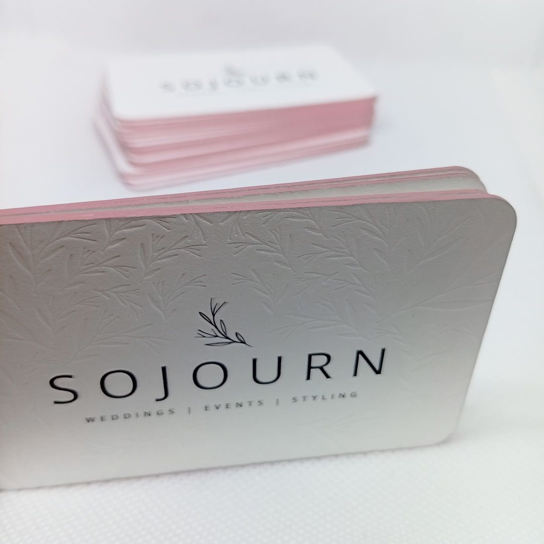 Stacked edge foiled business cards with front of card letterpress logo and in the out of focus business card stack in the background